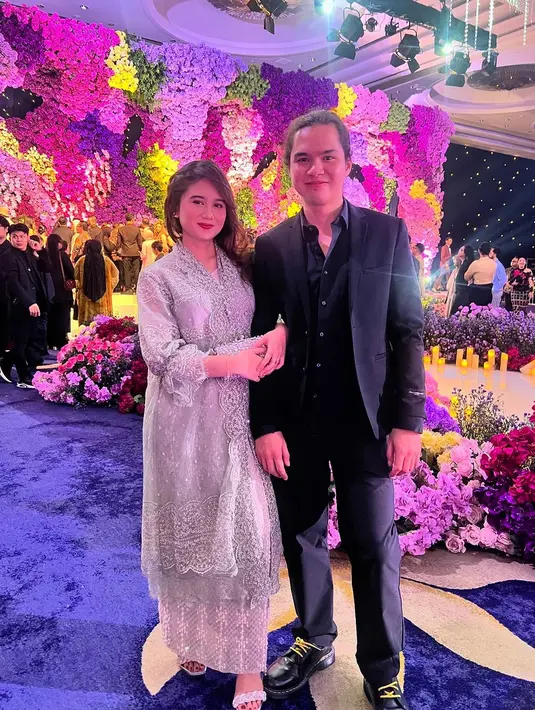 Lagi, gaya serasi pasangan Dul dan Tissa Biani ketika kondangan. Tissa tampil cantik dengan dress lace silver yang dipadu dengan rok panjang senada, sedangkan Dul kembali tampil serba hitam dengan setelan kemeja, jas, dan celana panjangnya. [Foto: Instagram/tissabiani]