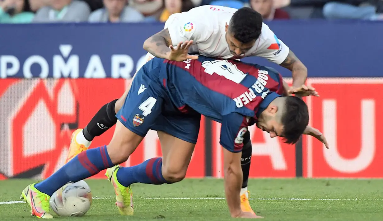 <p>Pemain Sevilla Jesus Manuel Corona alias Tecatito (kanan) berebut bola dengan pemain Levante Rober Pier pada pertandingan Liga Spanyol di Stadion Ciutat de Valencia, Valencia, Spanyol, 21 April 2022. Sevilla menang 3-2. (Jose Jordan/AFP)</p>