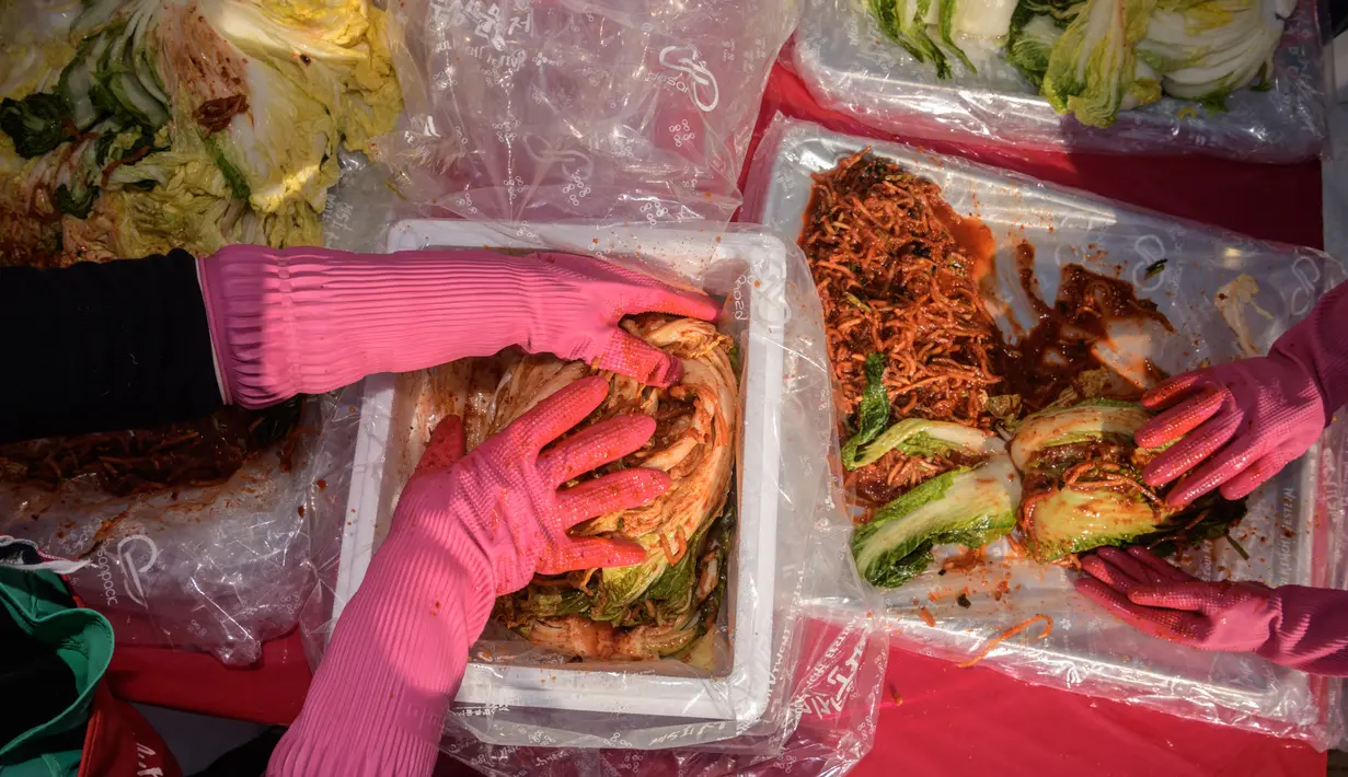 Peserta mempersiapkan kimchi selama berpartisipasi dalam festival pembuatan kimchi di Seoul (2/11). Festival pembuatan kimchi ini menandai awal musim dingin. (AFP Photo/Ed Jones)