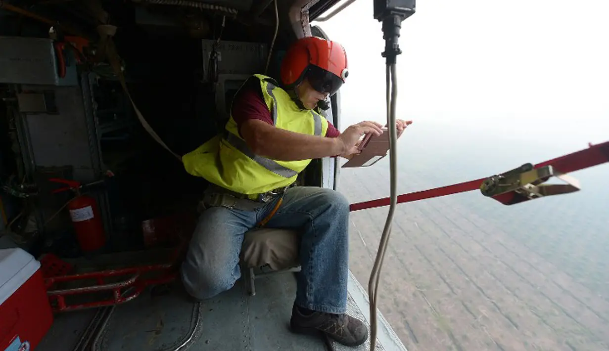 Seorang awak helikopter Kamov yang dioperasikan Basarnas mengambil foto selama operasi pemboman air di Pelalawan, Riau, Kamis (17/9/2015). Asap dari kebakaran hutan ini mengakibatkan aktivitas warga Riau dan sekitarnya terganggu (AFP Photo/Adek Berry)