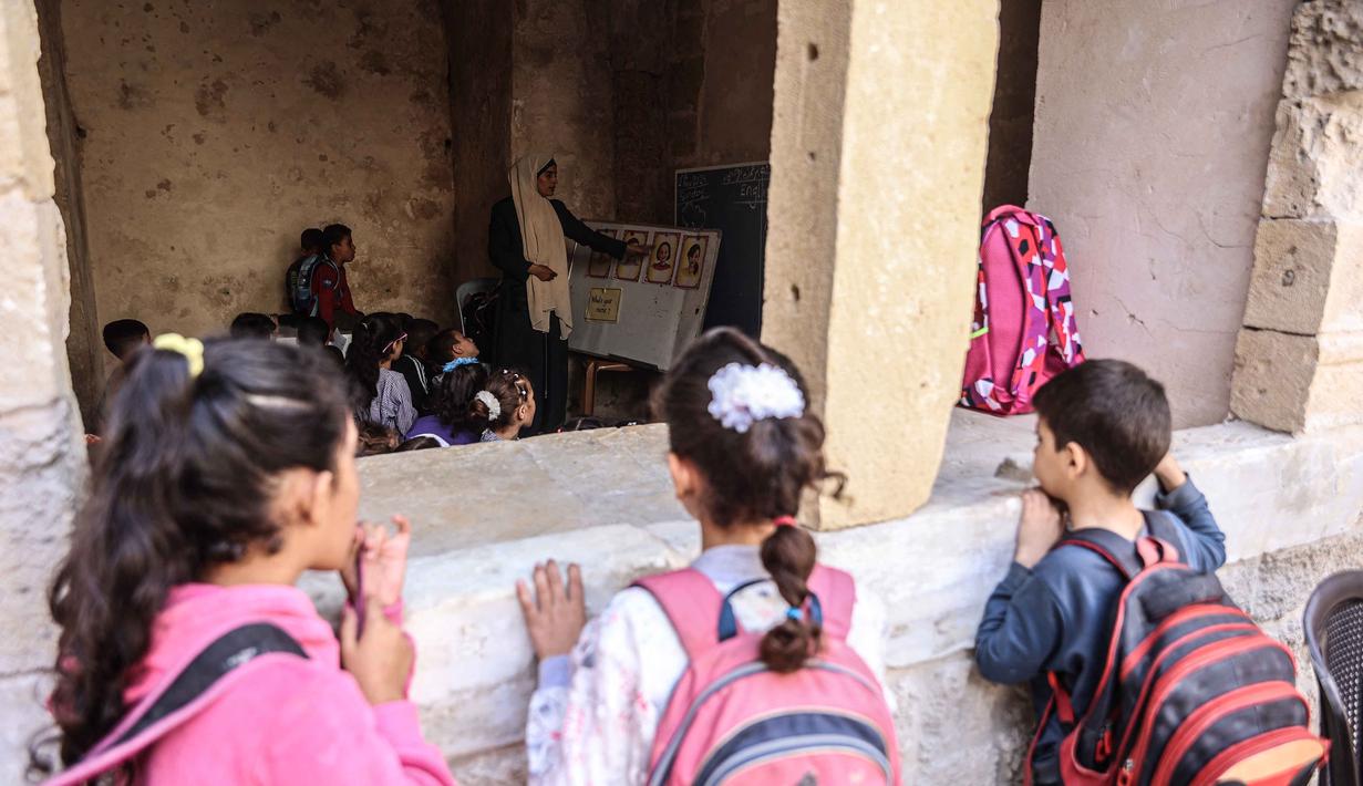 Anak-anak Palestina menghadiri kelas di sekolah bersejarah "Al-Kamaliya al-Othmanya" di Kota Tua Gaza yang menjadi bagian dari inisiatif sukarelawan yang diorganisir oleh para guru pengungsi, di Kota Gaza pada 2 November 2025. Badan Perserikatan Bangsa Bangsa (PBB) untuk Pengungsi Palestina (UNRWA) mengumumkan minggu ini, setelah dimulainya gencatan senjata antara Israel dan Hamas berlaku di Gaza, mereka membuka kembali beberapa sekolah di wilayah tersebut. (Omar AL-QATTAA/AFP)