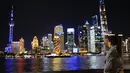 Seorang wisatawan merekam pertunjukan cahaya melalui ponsel di The Bund, Shanghai, China timur (4/11/2020). Sebuah pertunjukan cahaya bertema gelaran Pameran Impor Internasional China (China International Import Expo/CIIE) digelar di Lujiazui pada Rabu (4/11). (Xinhua/Zhang Haofu)