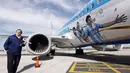 Dengan memegang sebuah replika, salah satu kru Bandara Ezeiza, Buenos Aires berfoto disamping pesawat yang akan digunakan untuk mengangkut Timnmas Argentina menuju Brasil, (3/6/2014). (REUTERS/Marcos Brindicci)