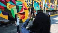 Warga foto di dekat karya seni Mural di Taman Ismail Marzuki (TIM), Cikini, Jakarta, Selasa (11/9). Mural tersebut dibuat oleh seniman asal Kolombia Diana Ordonez. (Liputan6.com/Faizal Fanani)