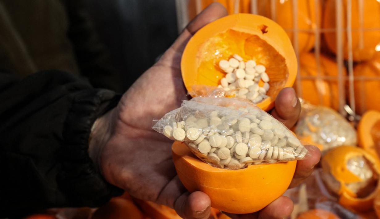 Seorang pria menunjukkan jeruk palsu berisi pil Captagon di Pelabuhan Beirut, Lebanon, 29 Desember 2021. Bea Cukai Lebanon menyita sembilan juta pil Captagon dalam jeruk palsu yang ditujukan ke salah satu negara Teluk. (ANWAR AMRO/AFP)