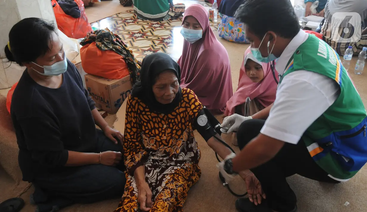 Paramedis memeriksa kesehatan pengungsi korban ledakan kilang minyak Balongan di Pendopo Kabupaten Indramayu, Senin (29/03/2021). Sekitar 900 warga saat ini mengungsi dari lima desa terdampak ledakan kilang minyak Balongan.  (merdeka.com/Arie Basuki)