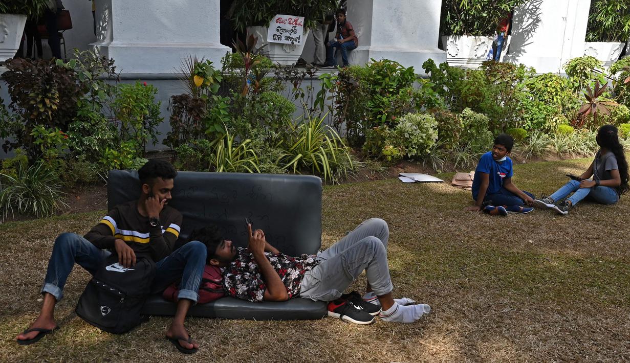 Orang-orang duduk di dalam kediaman resmi presiden Sri Lanka, beberapa hari setelah diserbu oleh pengunjuk rasa anti-pemerintah di Kolombo, Rabu (13/7/2022). Pengunjuk rasa yang kesal menyerbu istana dan kini menjadikannya sebagai spot untuk piknik hingga selfie. (Arun SANKAR / AFP)