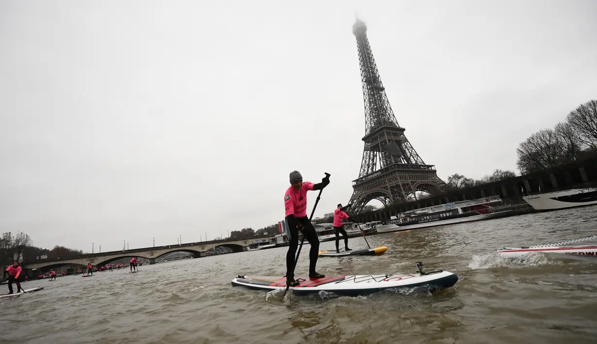 Peserta mengikuti perlombaan dayung sambil berdiri pada Nautic SUP Paris di sepanjang sungai Seine, Paris, Prancis, Minggu (3/12). Sekitar 700 peserta berpartisipasi menyeberangi sungai Seine dengan pemandangan kota Paris. (AFP PHOTO/CHRISTOPHE SIMON)
