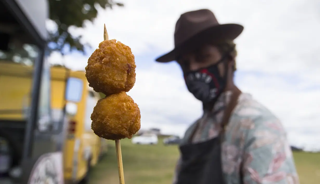 Seorang penjual yang mengenakan masker memperlihatkan bakso ayam goreng di Festival Ayam Goreng, Toronto, Kanada, 20 September 2020. Festival yang digelar di tengah pandemi COVID-19 tersebut berlangsung pada 19-20 September 2020 dengan menghadirkan sekitar 30 jenis ayam goreng. (Xinhua/Zou Zheng)