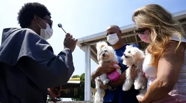 Seorang Fransiskan memberkati anjing peliharaan dalam misa untuk menghormati Santo Fransiskus dari Assisi pada Hari Raya Santo di Brasilia, Brasil, Senin (4/10/2021). Santo Katolik dianggap sebagai pelindung hewan. (AP Photo/Eraldo Peres)