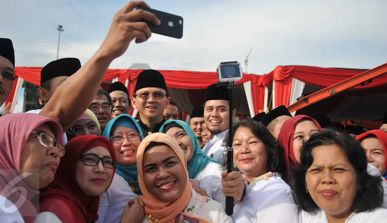 Gubernur DKI Basuki 'Ahok' Tjahaja Purnama berselfie bersama para PNS Pemprov DKI usai upacara peringatan hari ulang tahun Jakarta ke-489 di Lapangan Monas, Rabu (22/6). Upacara dihadiri seluruh pejabat lingkungan Pemprov DKI (Liputan6.com/Gempur M Surya)