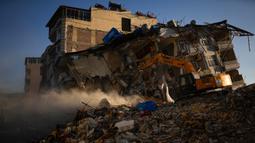 Ekskavator menghancurkan sisa-sisa bangunan yang hancur pascagempa di Samandag, Turki, 16 Februari 2023. Otoritas Turki mengatakan setidaknya 38.044 orang telah tewas, sementara pemerintah Suriah dan PBB mengatakan lebih dari 5.800 orang tewas di sana. (AP Photo/Francisco Seco)