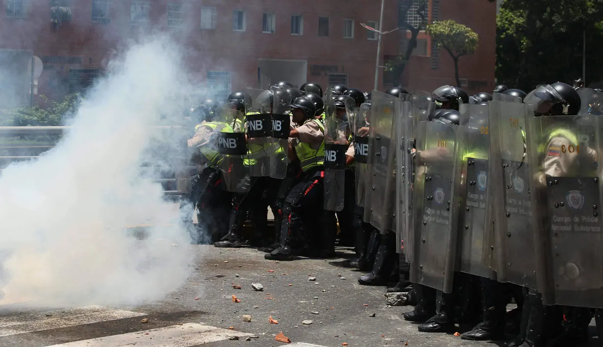 Seorang demonstran melemparkan gas air mata ke arah pasukan polisi di Caracas, Venezuela, (4/4). Mereka menuntut pemerintah menggembalikan kekuasaan kepada pihak opesisi. (AP Photo / Fernando Llano)