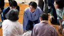 Perdana Menteri Jepang Shinzo Abe mengunjungi lokasi penampungan korban banjir di Mabi, Prefektur Okayama, Rabu (11/7). Sebelumnya, Abe sudah membatalkan rencana perjalanan luar negeri karena bencana yang kian memburuk. (AFP/Martin BUREAU)