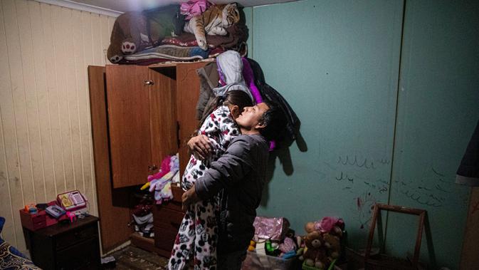 Jose Collantes memeluk sang putri, Kehity saat menidurkannya pada malam hari di rumah tempat mereka tinggal bersama saudara perempuan Jose, dua bulan setelah istrinya meninggal karena Covid-19 di Santiago, Chili, 17 Agustus 2020. 