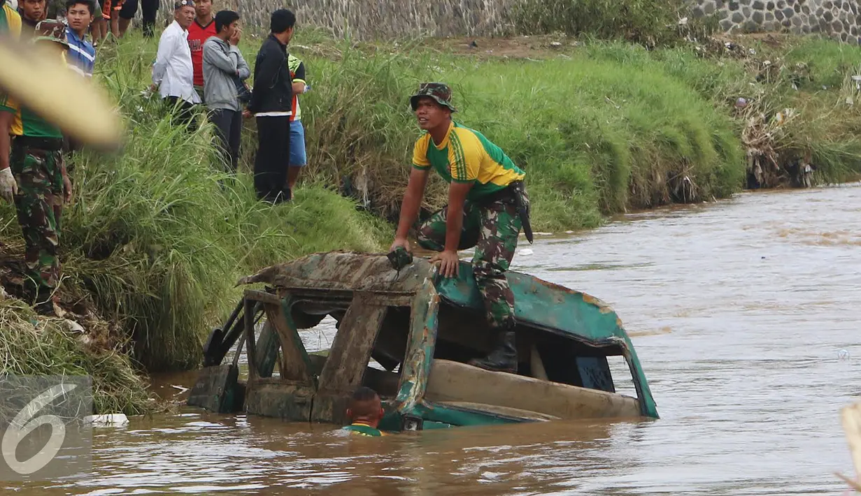 Prajurit Kostrad TNI AD memeriksa bangkai mobil yang diduga terdapat jenazah korban musibah banjir bandang di Cimacan, Garut (23/9). Data terakhir, korban jiwa mencapai 26 orang dan warga yang dilaporkan hilang 23 orang. (Liputan6.com/Johan Tallo)