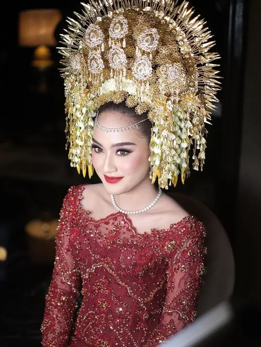 Area matanya dirias tajam dengan winged-eyeliner dan softlens cokelat, serta pulasan lipstik merah merona. [Foto: Instagram/rhay_david]

5.