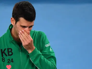 Petenis Serbia, Novak Djokovic, menangis saat diwawancara tentang Kobe Bryant seusai laga Australia Open 2020 di Melbourne, Selasa (28/1). Beri penghormatan dirinya memakai jaket inisial Kobe Bryant. (AFP/William West)