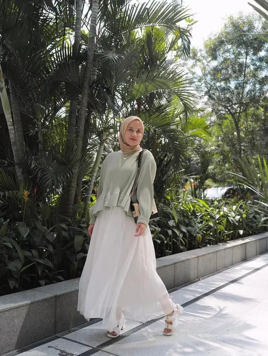 Untuk tampilan kasual yang nyaman namun tetap stylish, bisa sontek potret gaya Dwi yang satu ini. Padukan knit blouse warna sage, crinkle skirt warna putih, hijab warna nude, sling bag dan heels putih. (Instagram/dwihandaanda).