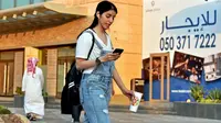 Manahel Otaibi, 25, memeriksa teleponnya saat dia berjalan dengan pakaian ala Barat di Tahlia Street, Riyadh, Arab Saudi, pada 2 September 2019. (Fayez Nureldine / AFP)