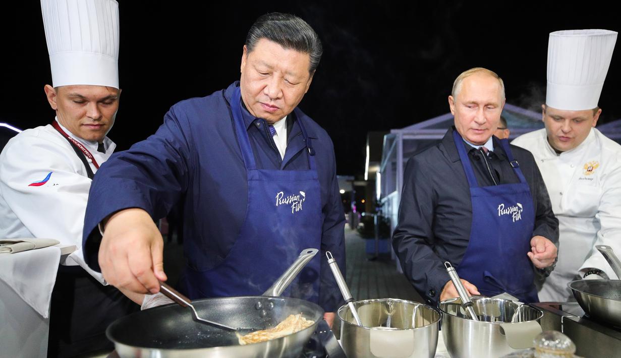 Aksi Presiden Rusia Vladimir Putin (dua kanan) dan Presiden China Xi Jinping (kedua kiri) saat membuat pancake bersama di sela acara Eastern Economic Forum di Vladivostok, Rusia, Selasa (11/9). (Sergei Bobylev/TASS News Agency Pool Photo via AP)