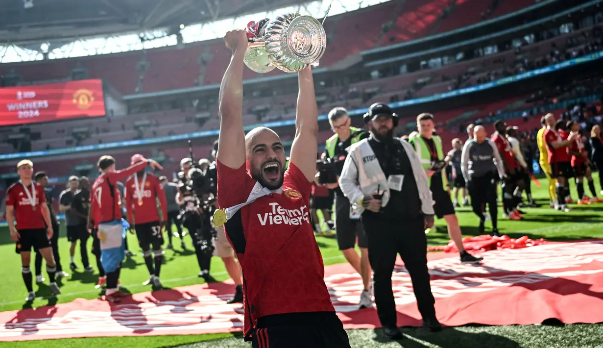 Pemain Manchester United, Sofyan Amrabat mengangkat trofi saat merayakan gelar juara Piala FA 2023/2024 di Stadion Wembley, London, Sabtu (26/05/2024). MU menang dengan skor 2-1 atas Manchester City di partai final. (AFP/Justin Tallis)
