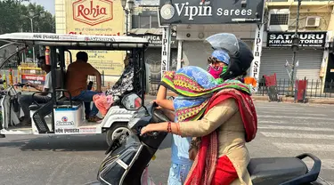 Seorang pengendara wanita menutupi kepala putrinya dengan syal untuk melindunginya dari panas yang menyengat di Lucknow, India, Sabtu, 18 Mei 2024. (AP Photo/Rajesh Kumar Singh)