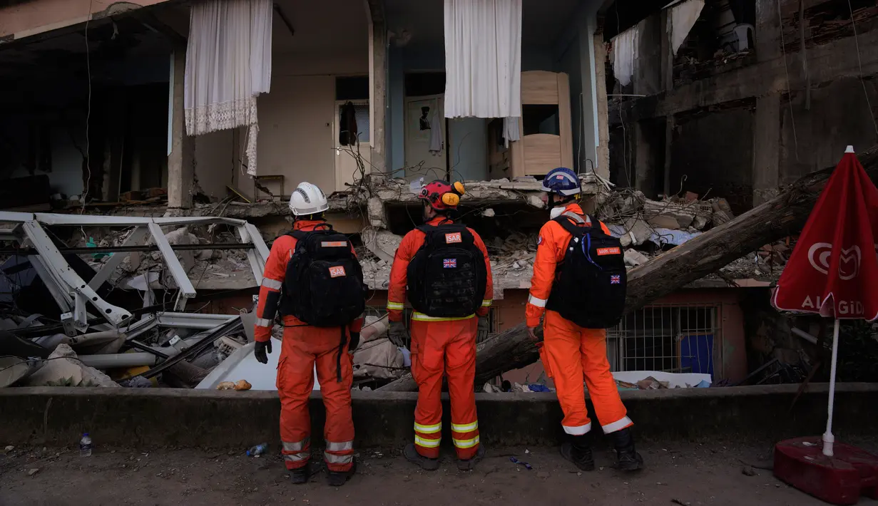 Anggota tim penyelamat Inggris melakukan pencarian di sebuah rumah yang hancur di Antakya, Turki, 9 Februari 2023. Puluhan ribu orang yang kehilangan rumah mereka dalam bencana gempa bumi berkerumun di sekitar api unggun dalam cuaca yang sangat dingin dan berteriak-teriak meminta makanan dan air, tiga hari setelah gempa melanda Turki dan Suriah. (AP Photo/Khalil Hamra)