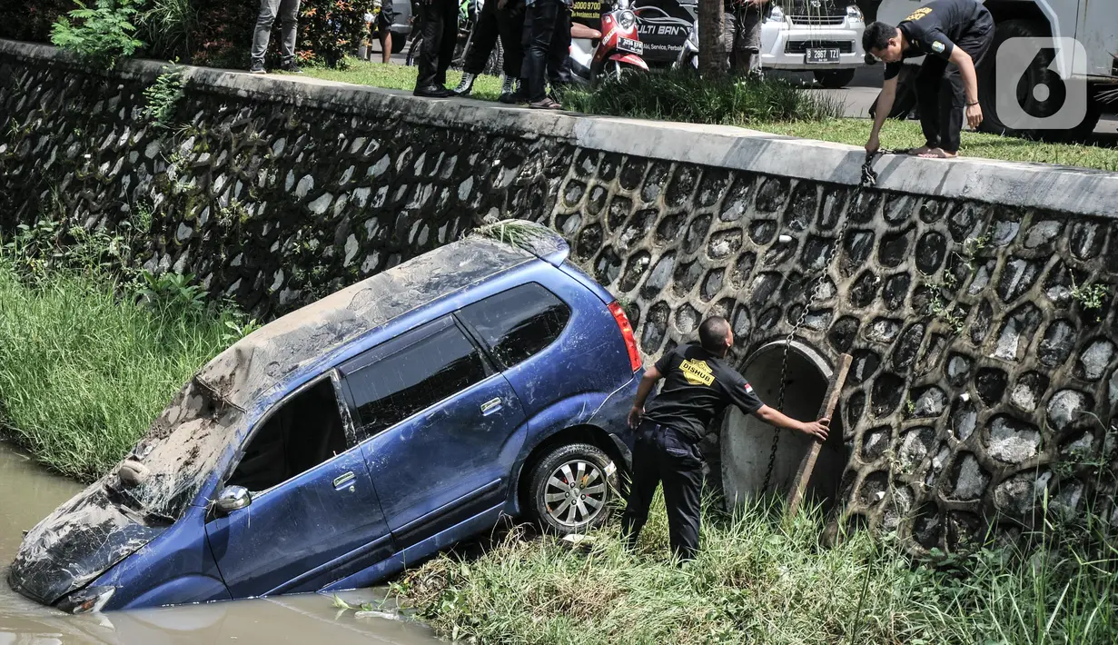 Petugas Dinas Perhubungan Kota Bekasi saat evakuasi mobil yang terperosok ke kali di Harapan Indah, Bekasi, Jawa Barat, Rabu (16/2/2022). Mobil jenis Avanza tersebut jatuh ke dalam kali usai mengalami kecelakaan tunggal akibat tergelincir saat melintasi tikungan. (merdeka.com/Iqbal S. Nugroho)