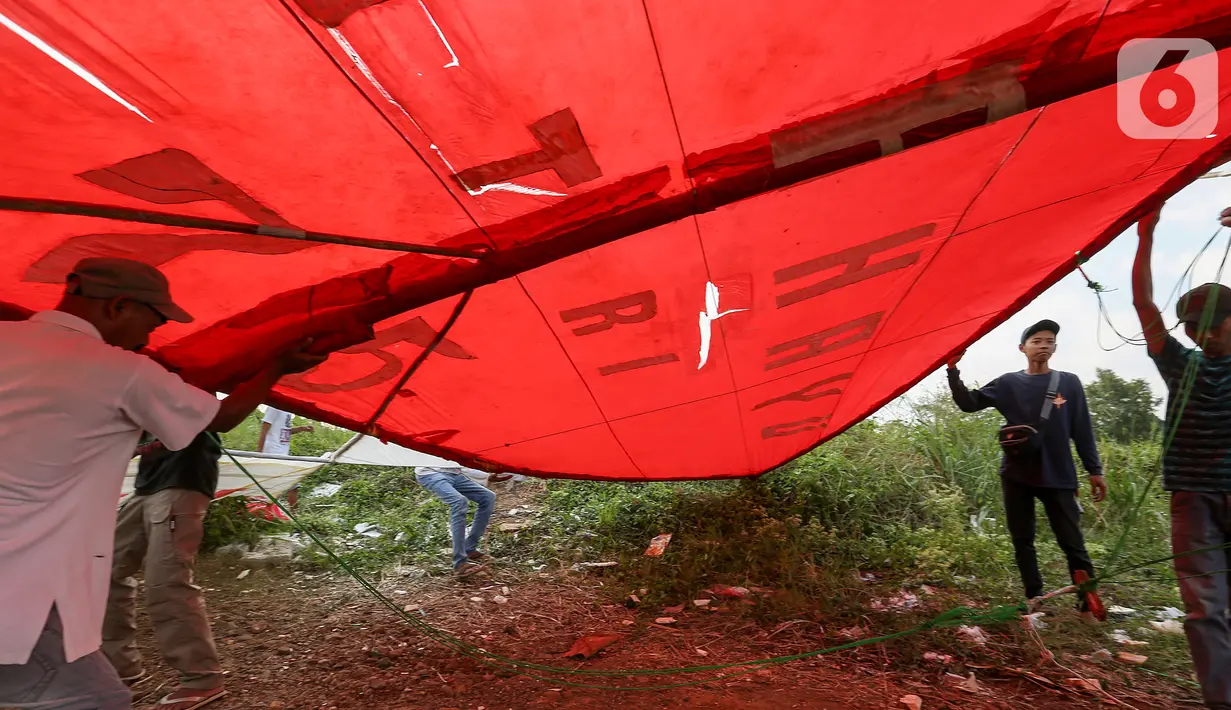 Warga menahan layang-layang merah putih raksasa sebelum diterbangkan di kawasan Bambu Apus, Tangerang Selatan, Senin (17/8/2020). Layangan berukuran 10 X 9 meter yang ditarik menggunakan tambang diterbangkan dalam rangka memperingati HUT Ke-75 RI. (Liputan6.com/Fery Pradolo)