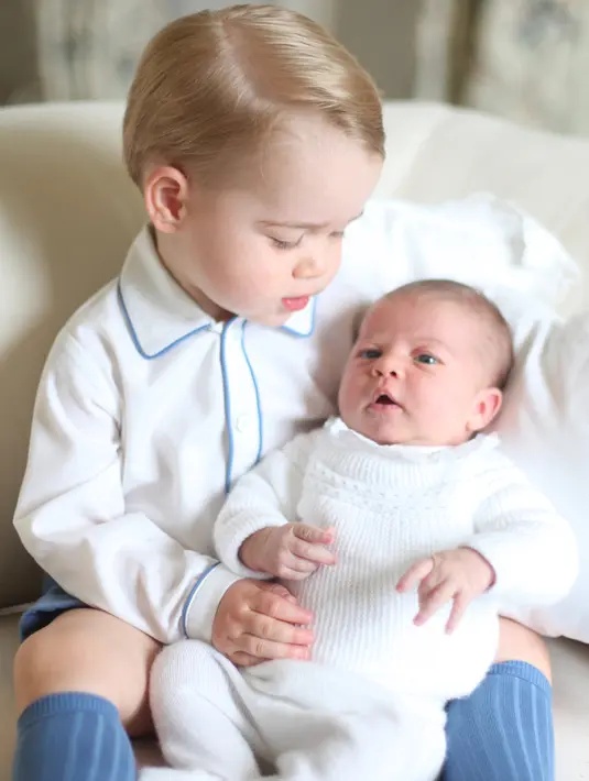 Dengan wajah lucunya, Pangeran George memandang sang adik, Putri Charlotte yang berada dipangkuannya saat bersantai di rumah mereka di Anmer Hall, Norfolk. Foto dirilis pada Sabtu, 6 Juni 2015.(REUTERS/Duchess of Cambridge)