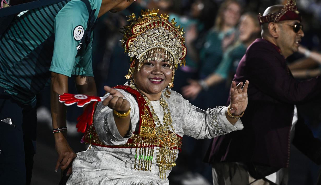 Atlet para-weghtlifting Indonesia, Siti Mahmudah menyapa para penonton saat upacara pembukaan Pralimpiade Paris 2024 yang berlangsung di jalan raya ikonis Kota Paris, Place de la Concorde, Paris, Prancis, Rabu (28/08/2024) waktu setempat. (AFP/Pool/Julien De Rosa)