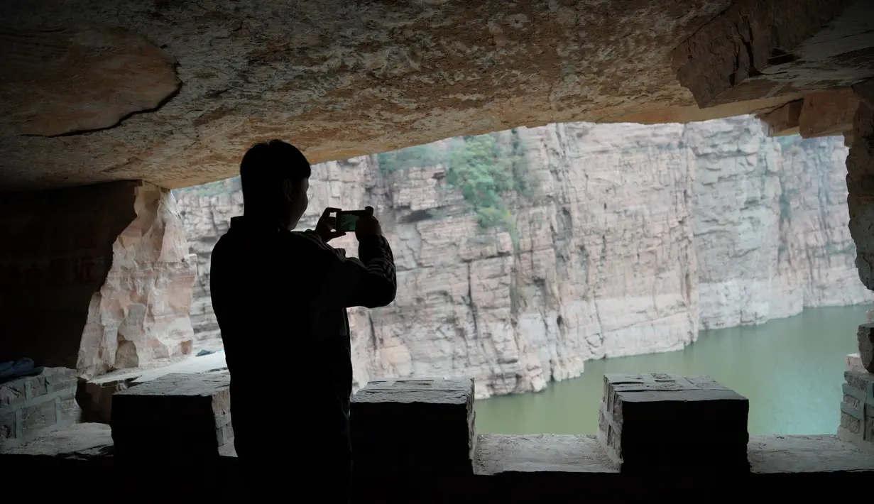 Seorang wisatawan memotret di jalur di tebing dekat Waduk Xiagou yang berada di Chaiguan, Kota Shahe, Provinsi Hebei, China utara, pada 28 Oktober 2020. Mengular berliku di sepanjang gunung, jalur tebing ini memiliki panjang 560 meter dan berada puluhan meter di atas permukaan air. (Xinhua/Mu Yu)