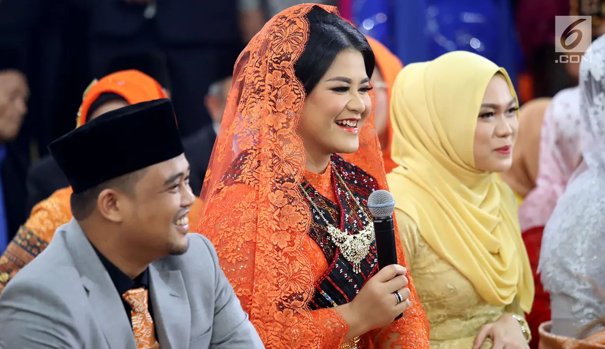 Kahiyang Ayu didampingi sang suami, Bobby Nasution mengucapkan terima kasih pada prosesi Mangalo alo Mora di Kompleks BHR-Tasbi, Medan, Jumat (24/11). Kahiyang dan Bobby kali ini kompak mengenakan pakaian bernuansa oranye. (Liputan6.com/Pool/Media Center)