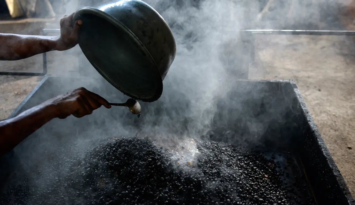 Seorang pria memasukkan biji kopi robusta untuk diolah menggunakan alat tradisional di salah satu industri rumah tangga di Ulee Kareng, Aceh, Rabu (20/11/2019). Kopi yang diolah secara tradisional itu dijual dengan kisaran harga beragam tergantung kualitas. (CHAIDEER MAHYUDDIN/AFP)