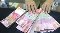 Pegawai menunjukkan mata uang rupiah di penukaran uang di Jakarta, Rabu (4/3/2020). Rupiah ditutup menguat 170 poin atau 1,19 persen menjadi Rp14.113 per dolar AS dibandingkan posisi hari sebelumnya Rp14.283 per dolar AS. (Liputan6.com/Angga Yuniar)