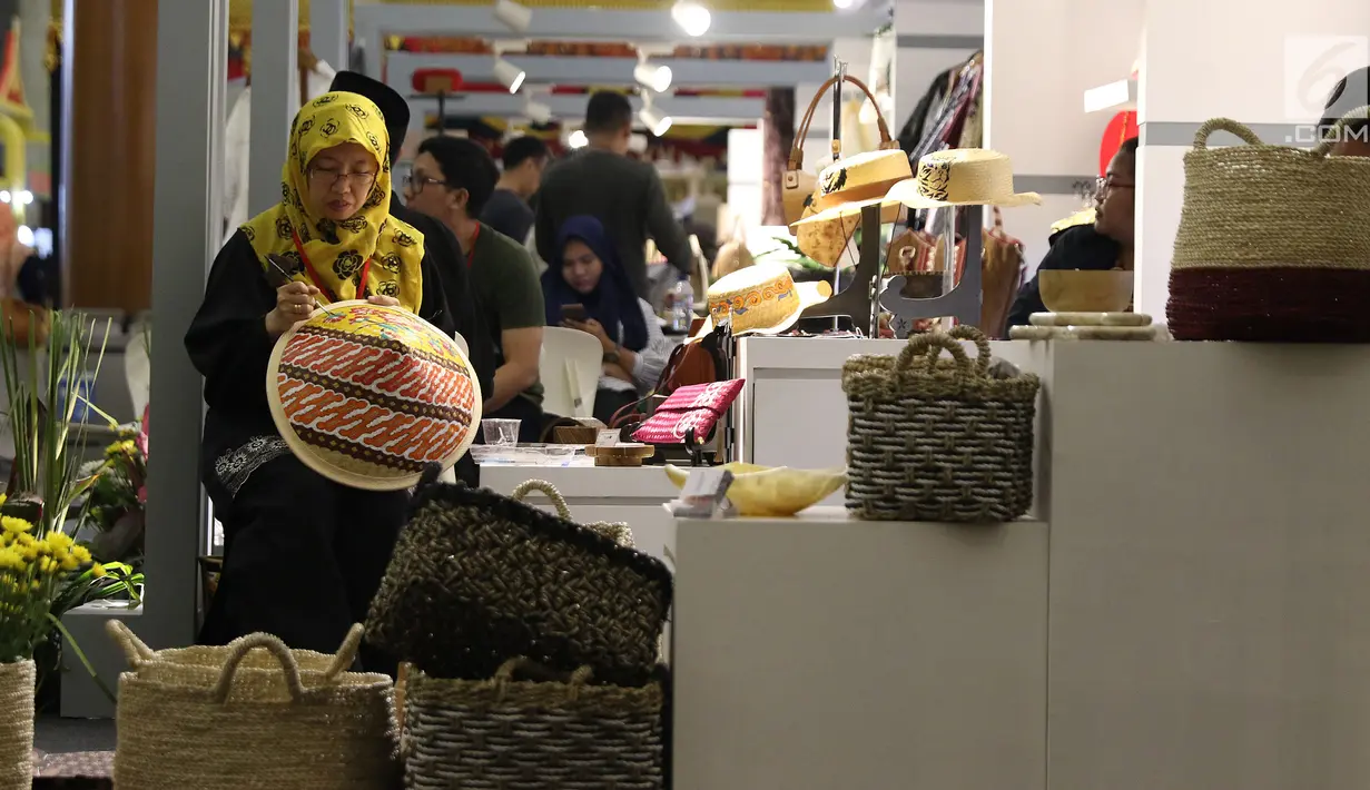 Pengrajin menghias salah satu topi caping yang dipamerkan pada KriyaNusa 2018 di Jakarta Convention Center, Jakarta, Sabtu (29/9). Terdapat 13 stand kriya dan 21 stand kuliner di KriyaNusa 2018. (Liputan6.com/Helmi Fithriansyah)