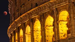 Fenomena gerhana bulan total "Micro Blood Moon" terlihat di dekat Colosseum di Roma, Italia, Jumat (27/7). Gerhana bulan yang terlama pada abad ini dapat disaksikan di seluruh dunia dengan mata telanjang. (AP/Gregorio Borgia)