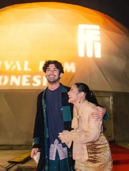 Tampil berdua menghadiri acara Festival Film, Prilly tampil anggun dengan organza top bernuansa keemasan, yang dipadu dengan mini skirt dari bahan beludru emas. Sedangkan Reza tampil dalam padu padan yang lebih edgy bernuansa biru kehijauan. Foto: Instagram.
