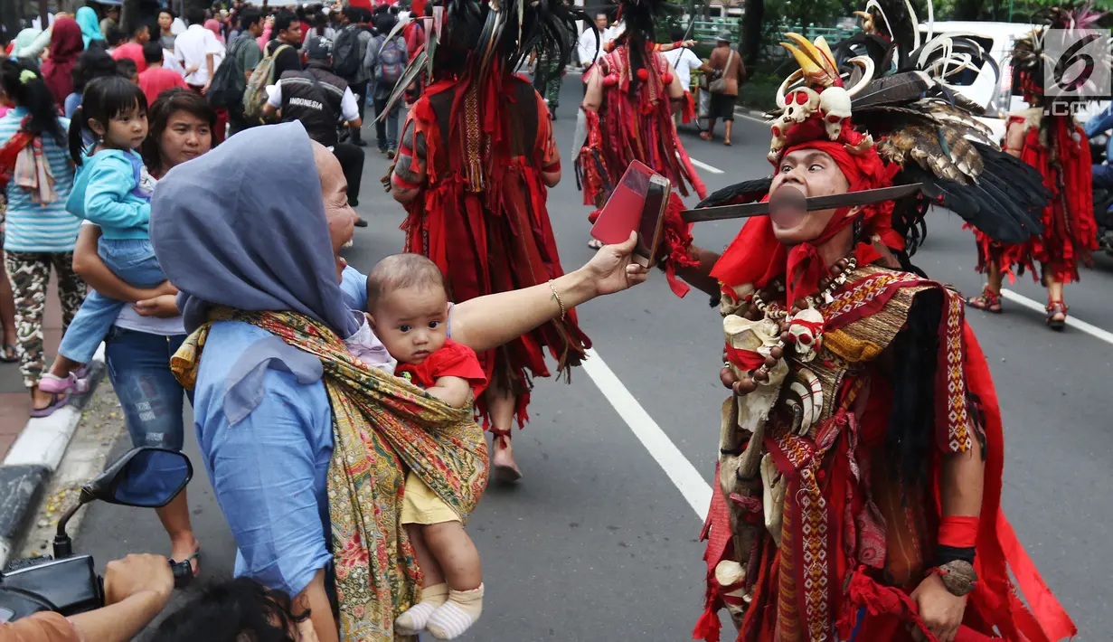 Warga mengambil gambar atraksi tatung dalam arak-arakan perayaan Cap Go Meh di kawasan Petojo, Jakarta, Selasa (19/2). Perayaan ini diselenggarakan oleh Wihara Bodhidharma (Lo Cia Bio). (Liputan6.com/Angga Yuniar)