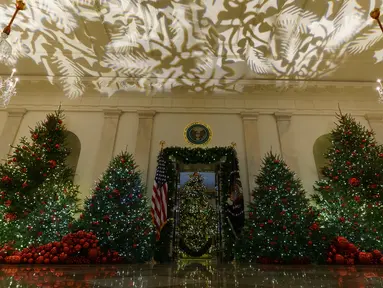 Ruangan The Grand Foyer dan Cross Hall dihiasi sejumlah pohon cemara yang didekorasi untuk perayaan Natal di Gedung Putih, Washington DC, Senin (26/11). Tema dekorasi yang diangkat tahun 2018 ini adalah 'American Treasures'. (AP/Carolyn Kaster)