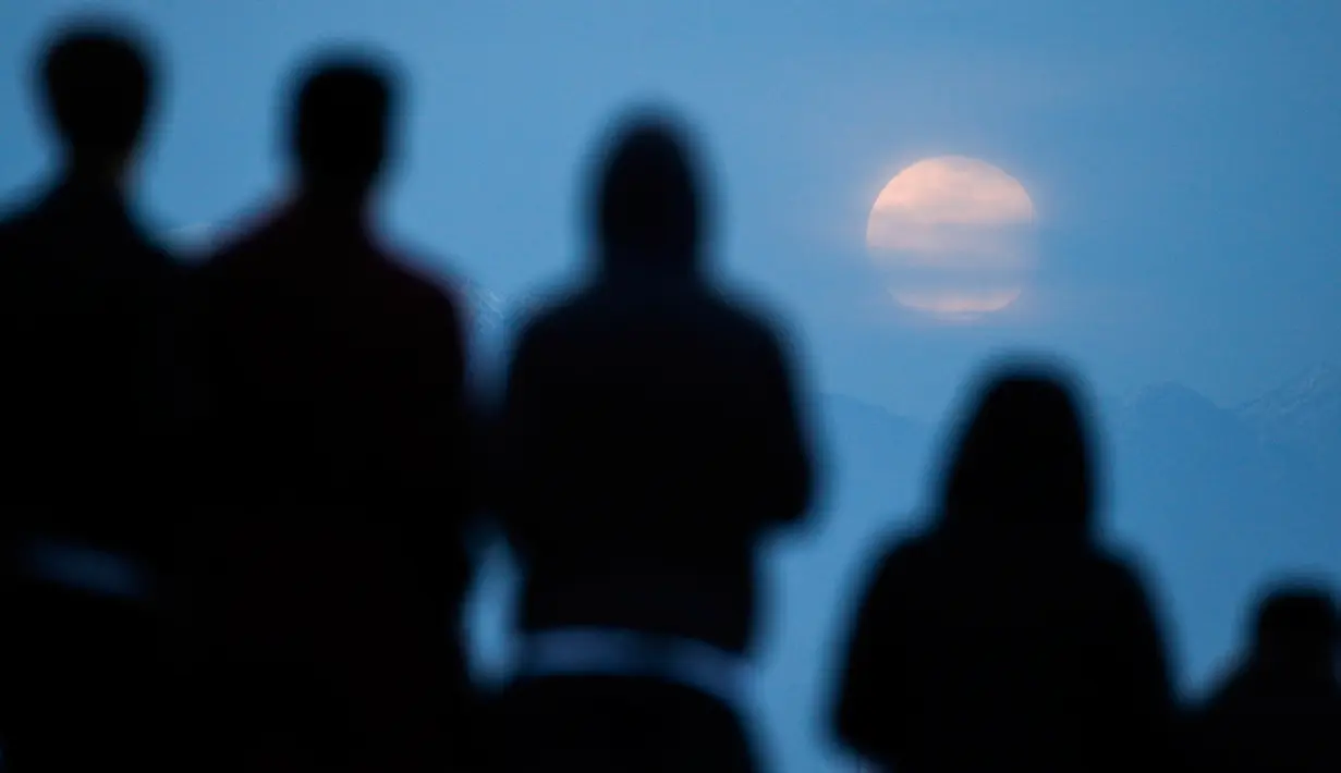 Orang-orang menyaksikan fenomena supermoon atau bulan super dengan latar belakang pusat kota Los Angeles dari Kenneth Hahn Park, Minggu (20/1). Supermoon akhir pekan ini adalah yang pertama terjadi pada tahun 2019 ini. (AP/Ringo H.W. Chiu)