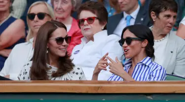 Duchess of Cambridge Kate Middleton dan Duchess of Sussex Meghan Markle berbincang saat menyaksikan pertandingan tenis dalam Kejuaraan Wimbledon di London, Inggris, (14/7). (AP Photo/Andrew Couldridge)