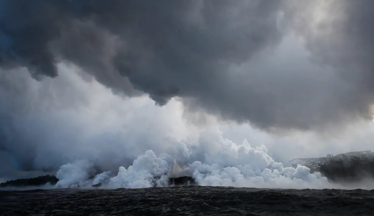 Gumpalan uap membumbung tinggi saat lava pijar mengalir ke laut dekat Pahoa, Hawaii, Amerika Serikat, Minggu (20/5). (AP Photo/Jae C. Hong)