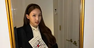 Nayeon tampil dengan blazer hitam oversize yang dikenakan sebagai luaran, dipadukan inner kemeja dan vest knit. Serta bawahan mini skirt pleated abu-abu. [@nayeonyny]