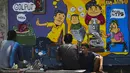 Sejumlah pria duduk di depan mural Pemilu 2019 di Banda Aceh, provinsi Aceh (17/3). Indonesia akan mengadakan pemilihan presiden dan parlemen secara serentak pada 17 April. (AFP Photo/Chaideer Mahyuddin)