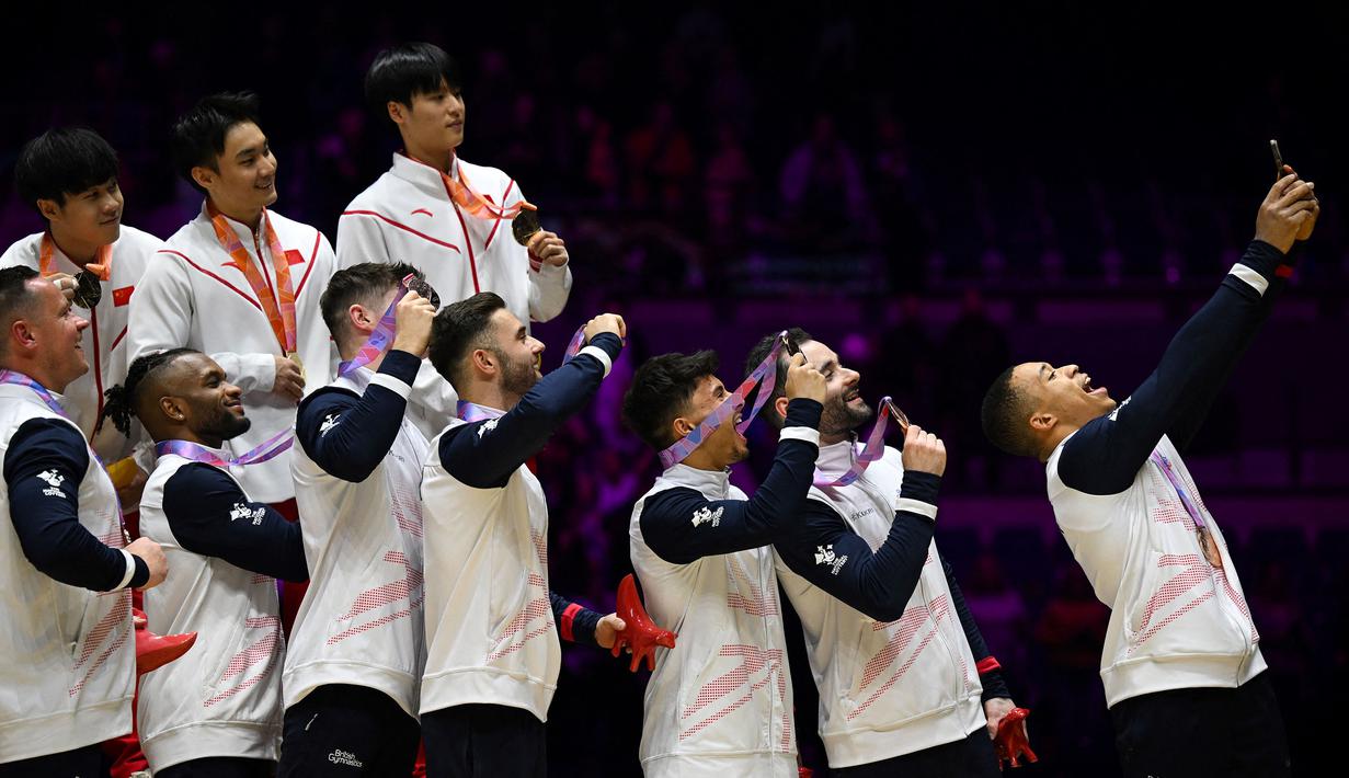 Pesenam Inggris, Joe Fraser (kanan) melakukan swafoto bersama dengan rekan setim dan pesaingnya saat mereka merayakan podium setelah bertanding dalam acara final beregu putra Kejuaraan Dunia Senam Artistik 2022 di Liverpool, Inggris, pada 2 November 2022. (AFP/Paul Ellis)