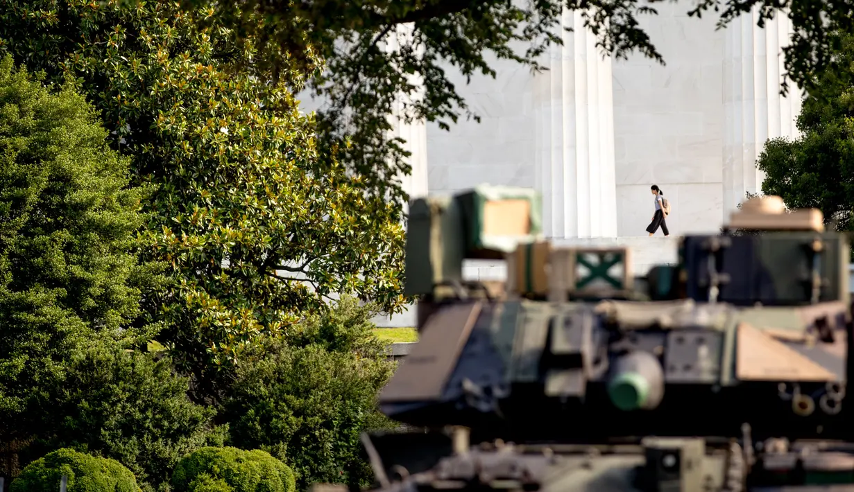 Seorang wanita berjalan ketika kendaraan pengangkut lapis baja Bradley terparkir di Lincoln Memorial, Washington, Rabu (3/7/2019). Presiden Donald Trump berencana memamerkan Tank-tank tempur sebagai bagian dari perayaan Hari Kemerdekaan AS yang dikenal sebagai Fourth of July. (AP/ Andrew Harnik)