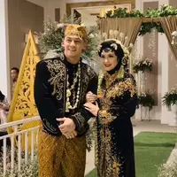 Revalina dan Samuel mengenakan baju adat Jawa warna hitam bahan velvet dengan aksen bordiran emas. Samuel mengenakan beskap lengkap dengan ronce melati dan blangkonnya.[@vatemat]