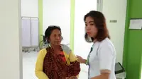 Seorang tenaga kesehatan di Puskesmas Jagoi Babang, Bengkayang, Kalimantan Barat membantu warga yang membawa anaknya untuk berobat (Liputan6.com/Giovani Dio Prasasti)